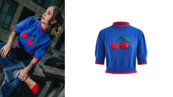 Dzianinowy sweter w intensywnie niebieskim kolorze z ozdobnym haftem dwóch czerwonych wiśni i zielonych liści na środku. Sweter posiada rękawy 3/4 oraz czerwone falbanki na mankietach, u dołu i przy dekolcie, nadające mu dziewczęcego i zabawnego charakteru. Idealny na chłodniejsze dni jako uroczy element casualowej stylizacji.