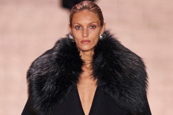 Anja Rubik na wybiegu Saint Laurent podczas prezentacji kolekcji na sezon jesień-zima 2022. Modelka jest w czarnym płaszczu z futrzanym kołnierzem, a na uszach ma srebrne kolczyki.