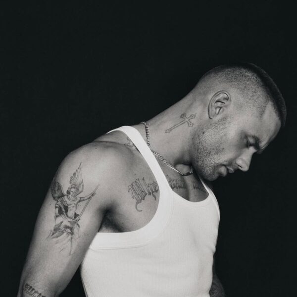 Liam Payne pozuje bokiem w białym podkoszulku, eksponując tatuaże na ramionach.