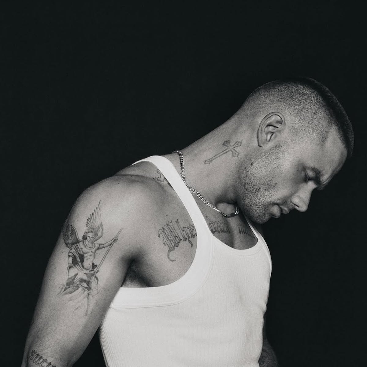 Liam Payne pozuje bokiem w białym podkoszulku, eksponując tatuaże na ramionach.