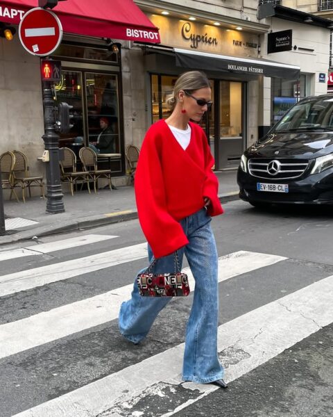 Streetwearowa stylizacja z czerwonym swetrem oversize, szerokimi jeansami i torebką Chanel, inspiracje modowe 2025