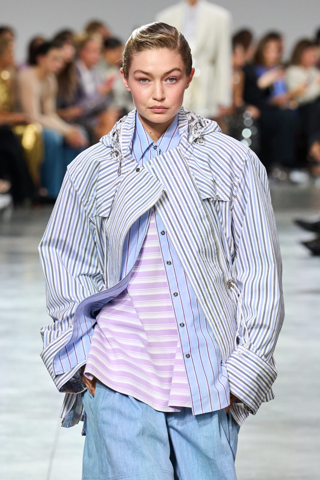 Trendy 2025 według AI: Modelka w pasiastych koszulach oversize w odcieniach bieli, błękitu i fioletu na pokazie mody.