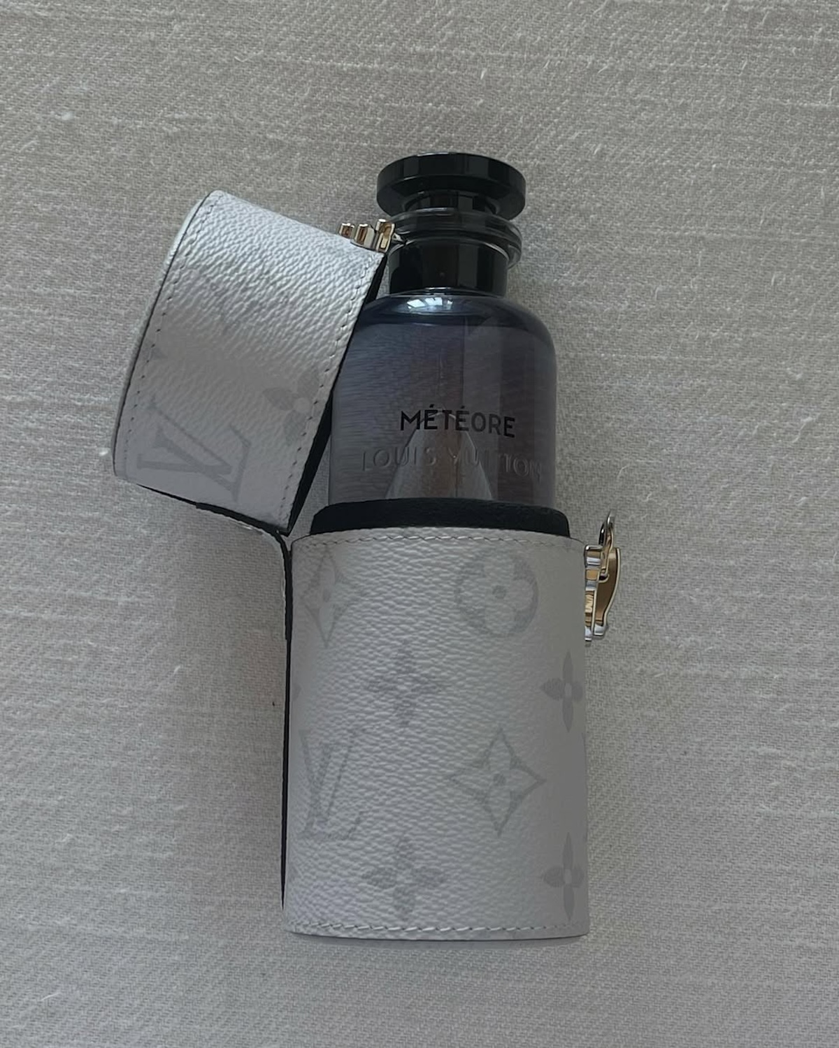 Najpiękniejsze perfumy damskie 2025: Louis Vuitton Méteore – luksusowy flakon z czarnym korkiem w ochronnym białym etui z logotypem marki.