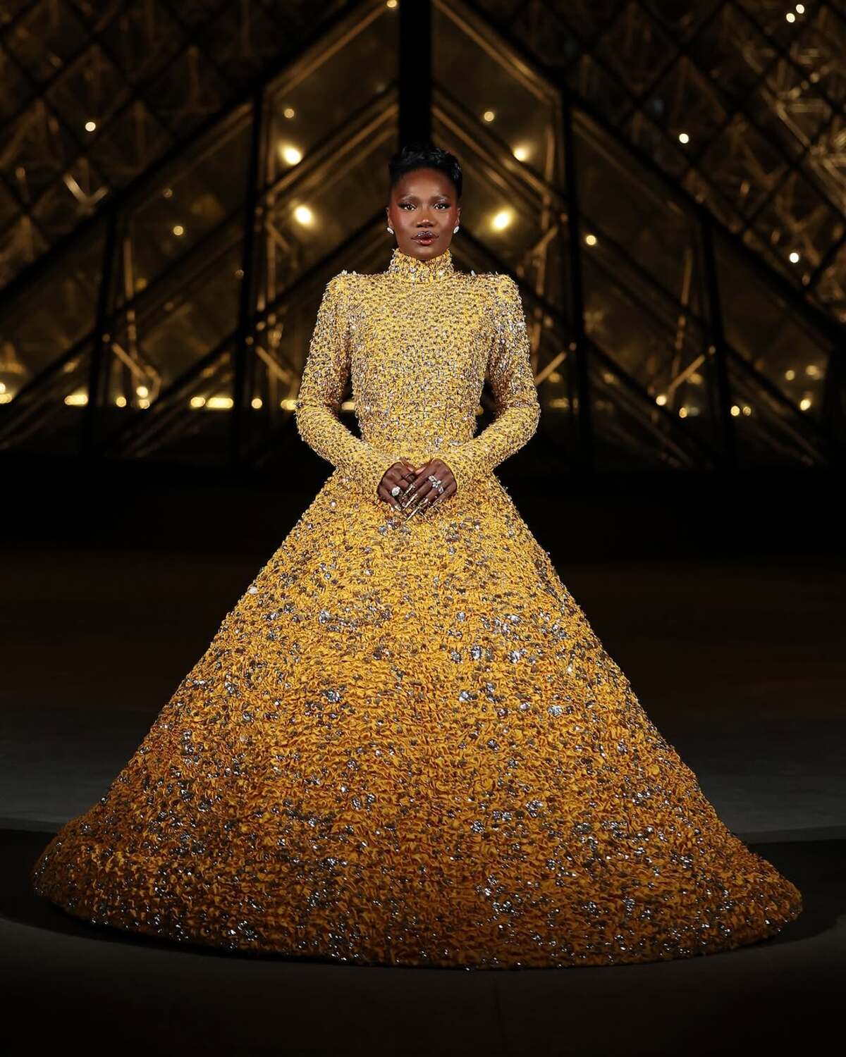 Europejska Met Gala 2025: Doechii zadała szyku w błyszczącej, żółto-złotej sukni. Zdjęcie przedstawia piosenkarkę pozującą przed Luwrem.