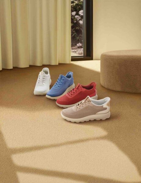 Geox Spherica Plus: Kompozycja trzech par sneakersów Geox Spherica Plus w różnych kolorach (beżowym, granatowym i niebieskim) ułożonych na szarych kaflach obok winylowej płyty na stole – zdjęcie podkreśla lifestyle’owy charakter kolekcji i jej dopasowanie do nowoczesnego wnętrza.