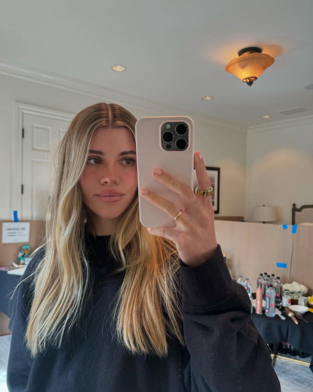 Modne kolory włosów 2025. Blondynka z długimi włosami robi sobie selfie z wygodnej bluzie.