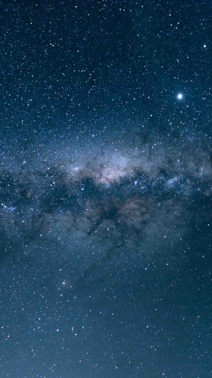 Horoskop dla Panny (21–27.04): Panoramiczne ujęcie nocnego nieba z szeroko rozciągniętym pasmem Drogi Mlecznej w odcieniach błękitu i szarości. Setki jasno świecących gwiazd tworzą hipnotyzujący wzór na tle ciemnej przestrzeni kosmicznej.