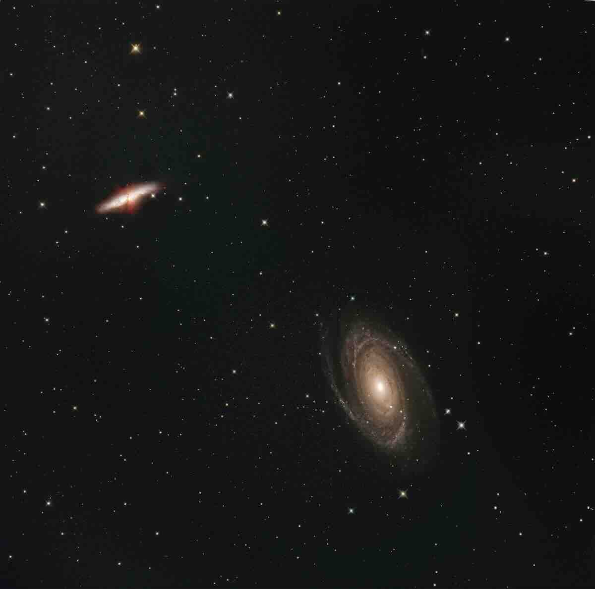 Horoskop tygodniowy dla Lwa (21–27.04): Fotografia głębokiego kosmosu przedstawiająca spiralną galaktykę w prawym dolnym rogu oraz czerwono-żółtą galaktykę soczewkowatą w lewym górnym rogu. Otoczone są setkami drobnych gwiazd, tworząc wrażenie nieskończoności i ogromu wszechświata.