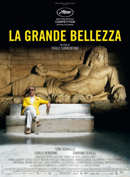 Plakat filmu 'La Grande Bellezza' w reżyserii Paolo Sorrentina; elegancki mężczyzna w żółtej marynarce i białych spodniach siedzi na marmurowej ławce przed monumentalną, starożytną rzeźbą półleżącego boga. Tytuł filmu w dużych, żółtych literach na czarnym tle w górnej części plakatu.