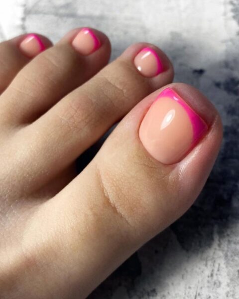 Zdjęcie stopy z pedicure w stylu french z różową końcówką na paznokciach. Stopa pozuje na marmurkowym tle.