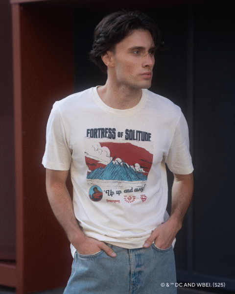 Model w kremowym t-shircie z grafiką „Fortress of Solitude” z limitowanej kolekcji Superman™ x Reserved i jasnych dżinsach; minimalistyczny kadr podkreśla ilustracyjny nadruk inspirowany ikoną komiksowego superbohatera.