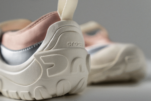 Ubraniowe FOMO na lato 2025: Zbliżenie na piętę buta Crocs EXP w pastelowej palecie (róż, krem, szarość); wyraźnie widać rzeźbioną, amortyzującą podeszwę i miękkie materiały, które łączą gorpcore’ową funkcjonalność z futurystycznym designem.