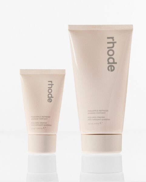 Dwa kremowe opakowania kosmetyku ‘Pineapple Refresh’ marki rhode – mniejsze o pojemności 40 ml i większe 150 ml; oba z napisem ‘PGA daily cleanser’.