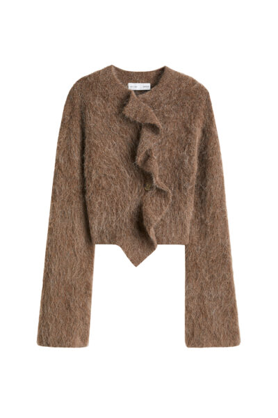 Trendy H&M jesień 2025: Puszysty sweter w ciepłym, brązowym odcieniu z efektowną falbaną biegnącą wzdłuż guzika. Zakończony w szpic, co podkreśla talię. Idealne połączenie przytulności z wyrazistym krojem.