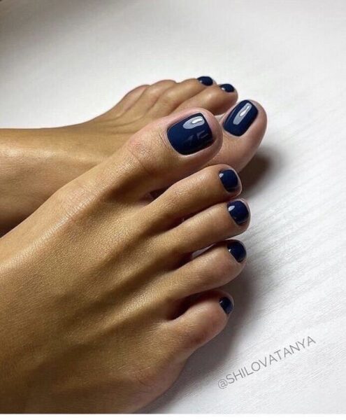 Granatowy pedicure na stopach – eleganckie paznokcie pomalowane na ciemny, głęboki odcień granatu z wysokim połyskiem. Klasyczna, minimalistyczna stylizacja, która sprawia, że stopy wyglądają zadbanie i nowocześnie.