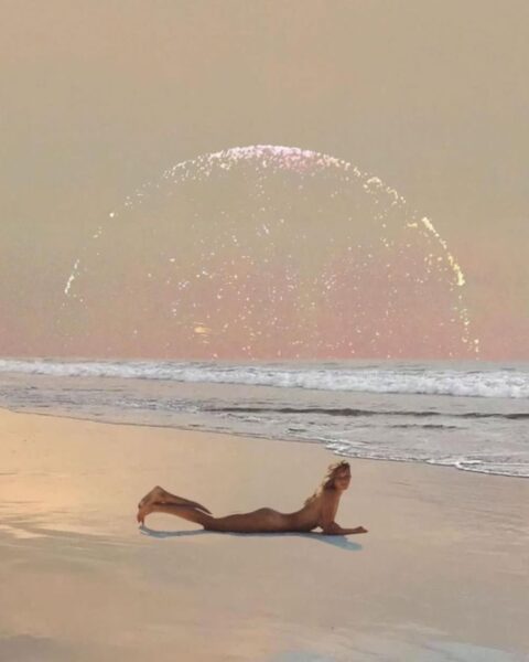 Ilustracja w ezoterycznym stylu. Jest na niej plaża i kobieta leżąca nago na brzuchu. W tle widać niebo z delikatnie zarysowanym sierpem księżyca na horyzoncie.