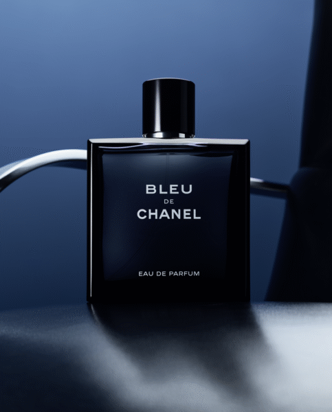 Flakon Bleu de Chanel Eau de Parfum w minimalistycznej aranżacji. Butelka w odcieniu głębokiego granatu stoi na gładkiej, ciemnej powierzchni z subtelnym refleksami światła, symbolizując luksus i ponadczasową elegancję.