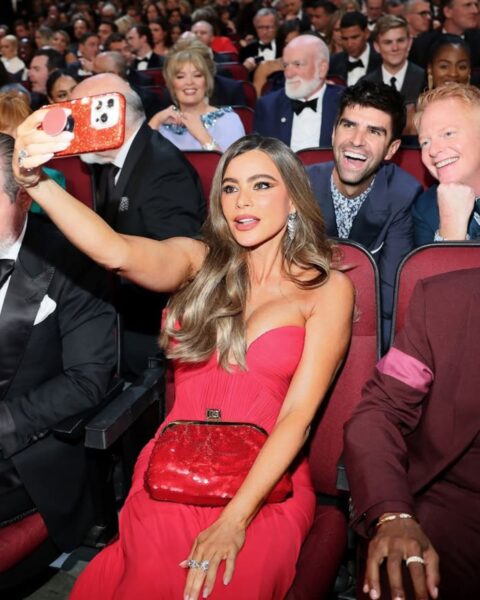 Zdjęcie z gali Emmy Awards. Widać gwiazdy siedzące na fotelach. Na pierwszym planie jest Sofia Vergara w czerwonej sukience, która robi selfie. Czekają na Emmy 2025 gift bagi.