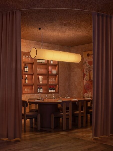 Eleganckie wnętrze restauracji z dużym drewnianym stołem, designerskim oświetleniem i półkami na wino, oddzielone zasłonami dla kameralnej atmosfery.