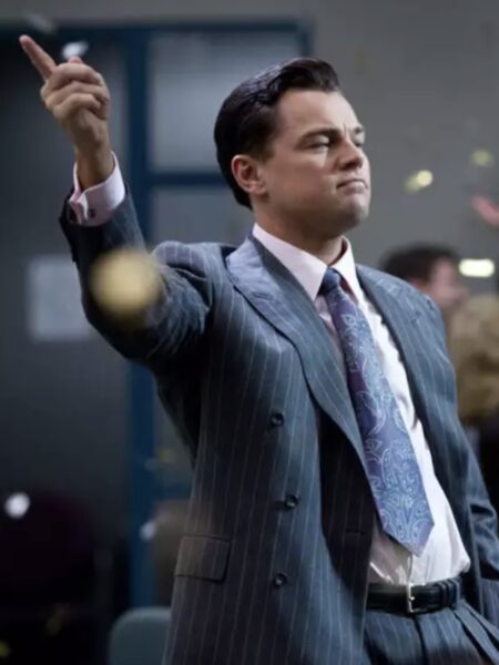 Leonardo DiCaprio jako Jordan Belfort w filmie „Wilk z Wall Street” (2013) – kadr przedstawia aktora w charakterystycznym pasiastym garniturze w odcieniu granatu, zaprojektowanym w duchu stylu Giorgio Armaniego. DiCaprio stoi pewnie, z uniesioną ręką, w otoczeniu rozsypujących się konfetti – symbolizując bezwzględną władzę, pieniądze i hedonizm lat 90.