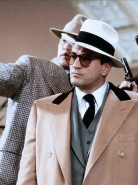 Robert De Niro jako Al Capone w filmie „Nietykalni” (1987) – aktor w charakterystycznym, dwurzędowym płaszczu Armaniego w kolorze karmelowym, uzupełnionym o kapelusz i ciemne okulary. Stylizacja balansuje między klasyką lat 30. a luksusem lat 80., nadając postaci teatralnej wręcz elegancji i groźnej charyzmy.