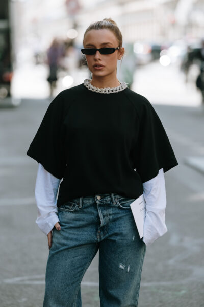 Najlepsze marki streetwear 2025: Kobieta w czarnym tshircie i czarnych okularach pozująca na ulicy.
