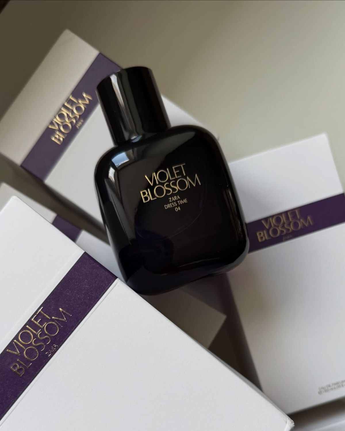 Perfumy z Zary na jesień 2025: na zdjęciu widać zapach Velvet Blossom w fioletowym flakonie ułożonym na pudełkach perfum.