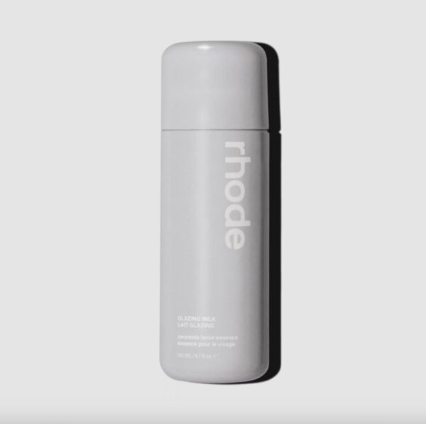 Rhode Glazing Milk – minimalistyczna butelka w jasnoszarym kolorze z białym napisem, mieszcząca esencję do twarzy stworzoną przez markę Hailey Bieber, słynącą z efektu „glazed skin”.
