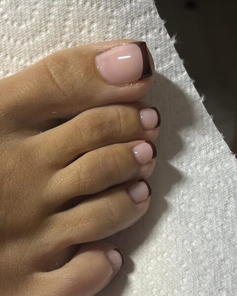 Jesienne wzory pedicure 2025: French pedicure w odcieniu mlecznego nude z ciemną, czekoladową końcówką – nowoczesna wariacja na temat klasycznego stylu, wpisująca się w trendy jesieni 2025 inspirowane minimalizmem i elegancją.