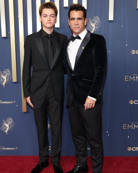 Na zdjęciu widzisz Colina Farrella i jego syna Henry'ego Tadeusza na czerwonym dywanie. Obaj są ubrani w eleganckie czarne smokingi. Colin ma na sobie aksamitną marynarkę, a jego syn gładką. Pozują na tle ścianki z logo Emmy.
