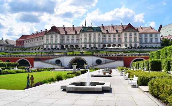 Ogrody Zamku Królewskiego w Warszawie z widokiem na barokową fasadę i fontanny w słoneczny dzień