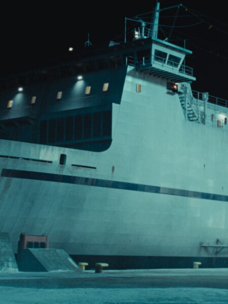 Ujęcie dużego statku pasażerskiego oświetlonego nocą. Monumentalna sylwetka jednostki odbija światło księżyca, tworząc chłodny, tajemniczy klimat portowego nabrzeża.