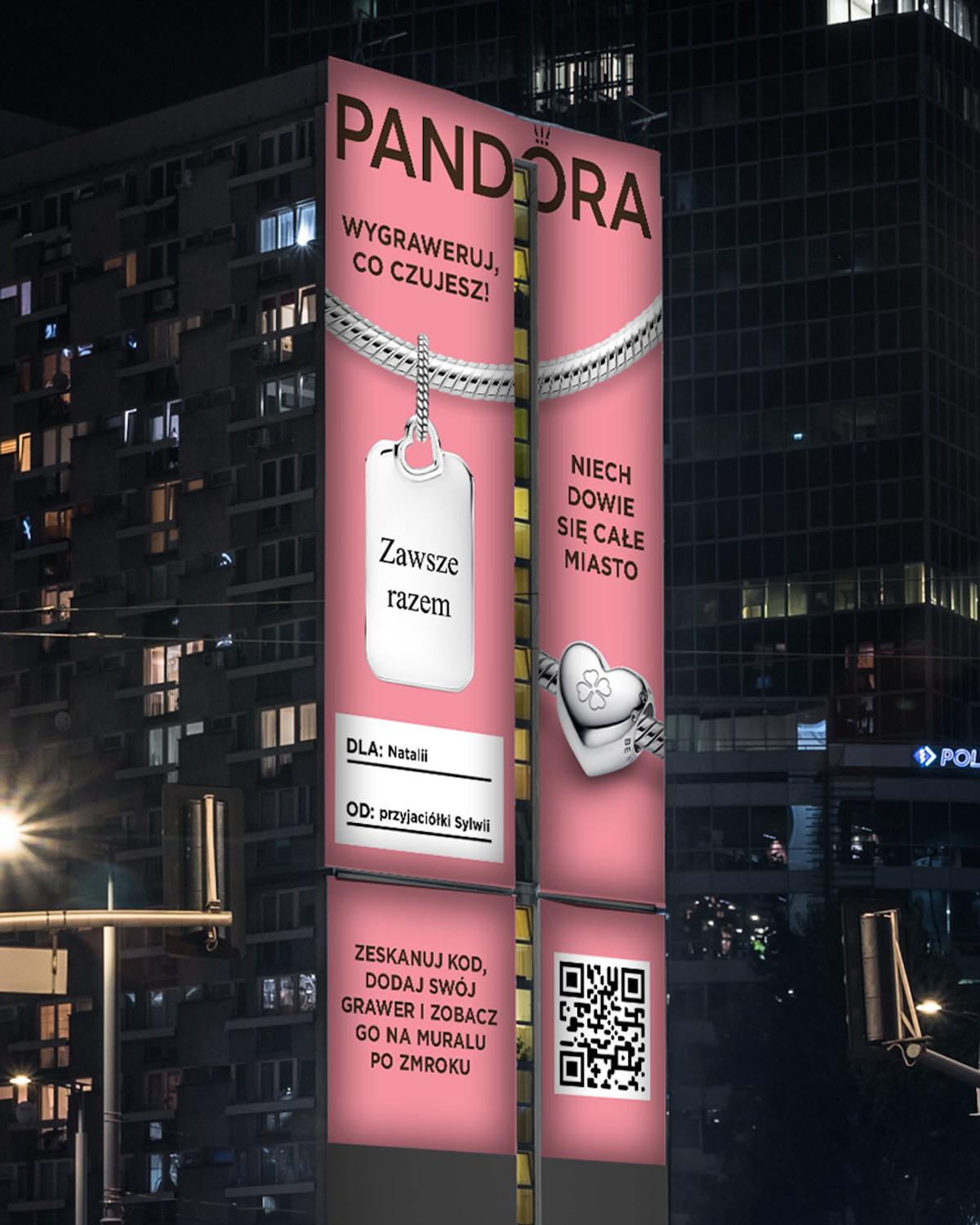 Pandora mural na rondzie ONZ: Wielkoformatowy mural reklamowy marki Pandora w centrum Warszawy. Na tle intensywnego różu widnieje hasło „Wygraweruj, co czujesz! Niech dowie się całe miasto” oraz srebrna bransoletka z zawieszką w kształcie blaszki z napisem „Zawsze razem”.