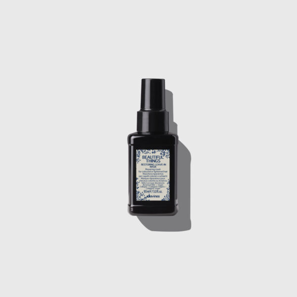 Czarne, minimalistyczne opakowanie Davines Beautiful Things Restoring Leave-In Mask na jasnym tle. Maska bez spłukiwania przeznaczona do włosów farbowanych, z roślinnymi składnikami i elegancką etykietą w stylu aptecznym.