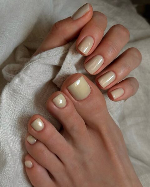 Kremowy, beżowy manicure i pedicure w odcieniu waniliowym (tiulowy pedicure), idealnie harmonizujący z jasną pościelą i symbolizujący naturalną, spokojną elegancję.