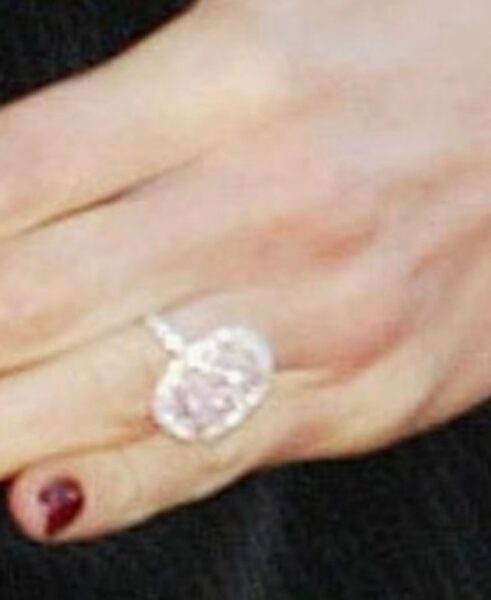 Zbliżenie na dłoń Victorii Beckham ozdobioną pierścionkiem zaręczynowym z różowym diamentem w kształcie serca, otoczonym brylantami; symbol jej pierwszych lat małżeństwa z Davidem Beckhamem.