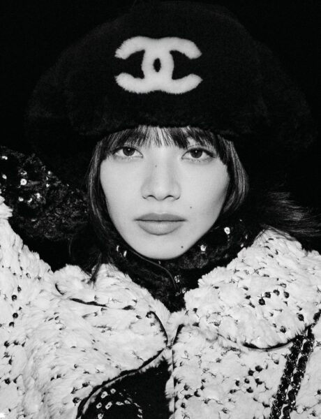 Czarnobiały portret kobiety w czapce uszance Chanel z dużym białym logo CC. Stylizacja z cekinową kurtką i futrzanymi wykończeniami tworzy luksusowy, retro-winter look inspirowany alpejskim glamour.