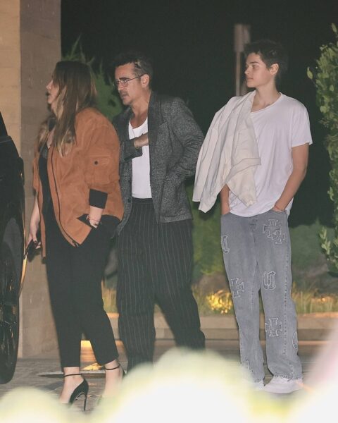 Trzy osoby, aktor Colin Farrell (w środku), jego syn Henry Tadeusz Farrell (po prawej) i Alicja Bachleda-Curuś (po lewej), stoją na zewnątrz nocą. Colin Farrell ma na sobie biały podkoszulek, szarą marynarkę w kratę i ciemne spodnie w paski, oraz okulary. Młody mężczyzna w białym T-shircie i jasnych, szerokich dżinsach z dużymi, ozdobnymi krzyżami po bokach, ma przerzuconą jasną kurtkę przez ramię i trzyma ręce w kieszeniach. Alicja Bachleda-Curuś ma na sobie czarną bluzkę, czarne spodnie, brązową kurtkę typu bomber i czarne szpilki. Wszyscy patrzą w lewo.