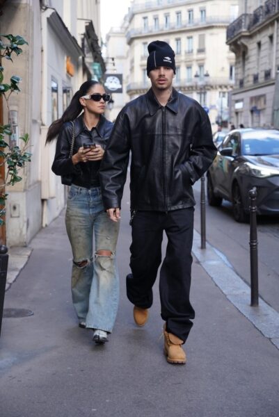 Kim Turnbull idzie ulicą w Paryżu obok Romea Bekchama. Kim ma na sobie czarną, skórzaną kurtkę, szerokie, postarzane dżinsy z przetarciami i czarne okulary przeciwsłoneczne. Włosy ma związane w kucyk. Mężczyzna idący obok niej ma na sobie czarną czapkę, czarną skórzaną kurtkę i czarne spodnie, a także musztardowe buty. Oboje idą chodnikiem, a w tle widać kamienice i samochód.