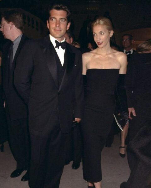 Carolyn Bessette-Kennedy i John F. Kennedy Jr. na wieczornej gali. Ona w czarnej sukni bez ramiączek i rękawiczkach.