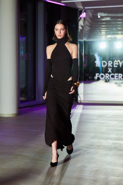 Czarna długa suknia z golfem i rozcięciem na biodrach oraz dopasowanymi rękawami – minimalistyczny, nowoczesny look z pokazu HDRÈY x FORCER. Kreacja podkreśla figurę i ma charakter haute eveningwear.