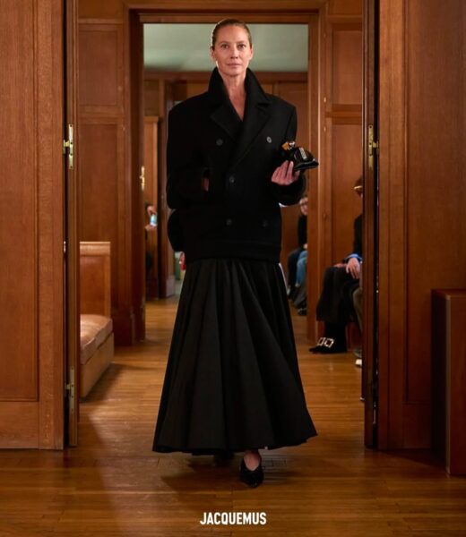 Christy Turlington: Współczesne ujęcie supermodelki, idącej pewnym krokiem po wybiegu w masywnym, czarnym płaszczu i obszernej spódnicy podczas pokazu Jacquemus. Fotografia ta znakomicie podkreśla jej dojrzałą elegancję i rolę jako wciąż aktywnej ikony, łączącej dziedzictwo mody lat 90. ze współczesnymi trendami.