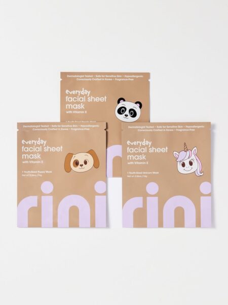 Zestaw trzech maseczek w płacie dla dzieci marki Rini, zaprojektowanych z wizerunkami uroczego pieska, pandy i jednorożca. Na opakowaniach widnieją informacje o witaminie E i formule odpowiedniej dla skóry wrażliwej. Zdjęcie produktowe utrzymane w minimalistycznym, pastelowym stylu.