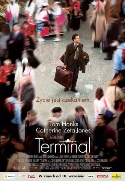 Plakat wzruszającego filmu na poprawę humoru "Terminal". Tom Hanks jako Viktor Navorski, w garniturze i z brązową walizką w dłoni, stoi samotnie na środku zatłoczonego holu lotniska, otoczony rozmazanymi postaciami spieszących się ludzi. Patrzy w górę, wyglądając na zdezorientowanego. Nad tytułem widnieje hasło: "Życie jest czekaniem.".