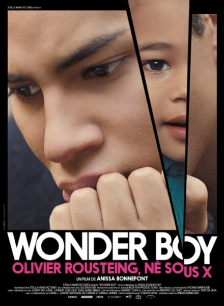 Plakat do filmu "Wonder Boy, Olivier Rousteing, né sous X" (znanego w Polsce jako "Olivier Rousteing: Cudowne dziecko świata mody"). Plakat przedstawia duże zbliżenie na zamyśloną twarz Oliviera Rousteinga, który trzyma pięść blisko ust. W prawym górnym rogu, przez ukośne "cięcie" w obrazie, widać fragment twarzy małego chłopca.