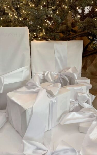 Eleganckie prezenty święta 2025: Pięknie zapakowane pudełka w biały papier i wstążkę.