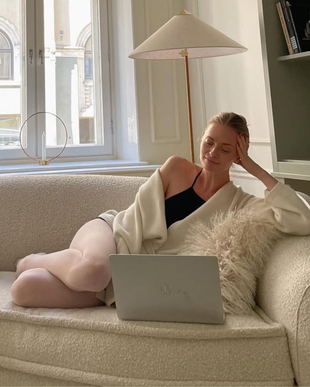 Kobieta w stylizacji balletcore odpoczywa na jasnej kanapie z laptopem, sprawdzając najbardziej wyczekiwane premiery filmowe 2026 w przytulnym, eleganckim wnętrzu.