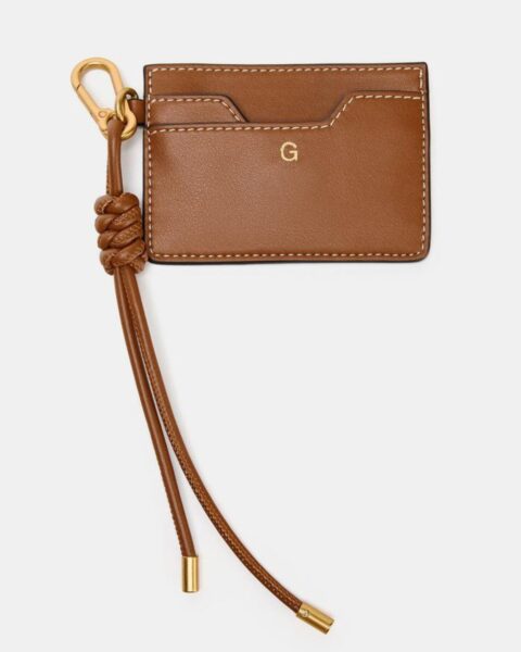 Skórzane etui na karty w kolorze karmelowym, z ozdobnym, plecionym brelokiem i złotym karabińczykiem. Stylowy organizer do torebki, akcesorium dla eleganckich kobiet, inspiracja na prezent.