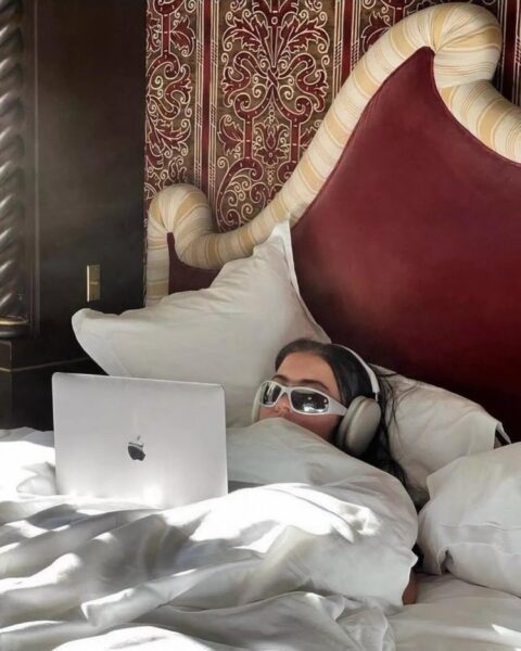 Skandynawskie filmy na weekend świetnie pasują do spokojnego oglądania w domowym zaciszu – na zdjęciu widać osobę leżącą w łóżku z laptopem i słuchawkami, zanurzoną w seansie. Ciepłe światło i miękka pościel podkreślają intymny, wyciszony klimat idealny na filmowy reset.