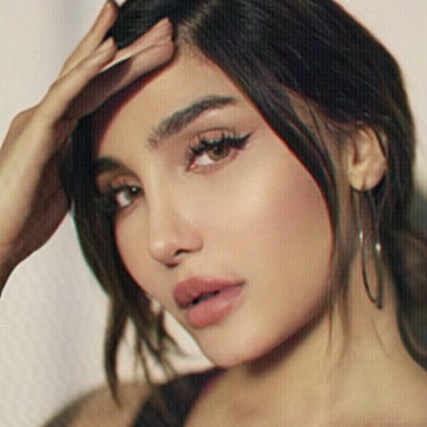 To jest portret zbliżeniowy, który eksponuje klasyczny, ale jednocześnie wyrazisty makijaż oczu z graficzną, przedłużoną kreską typu "foxy eye". Usta są podkreślone neutralną, matową szminką w kolorze zgaszonego różu, co doskonale równoważy mocniejszy akcent na powiece. Takie odważne, ale eleganckie akcenty na oczach z pewnością dominują w makijażowych trendach 2026, zwłaszcza te inspirowane estetyką lat 90.